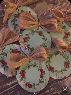 christmas cookies with bows on them sitting on top of a wooden table next to twine ribbons