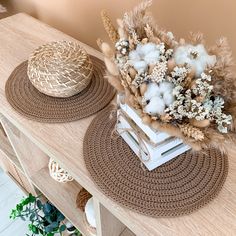 two baskets with flowers on top of a wooden table next to a basket filled with cotton