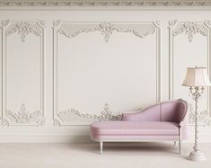 a pink chaise lounge in front of a white wall with ornate paneled panels