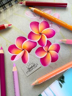 some colored pencils are laying next to each other on a table with flowers drawn on it