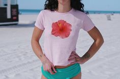 Are you craving that 2000s and 90s nostalgia? We've got you covered with this adorable Hibiscus Flower Baby Tee - bringing your Y2K outfit dreams to life! Our adorable Y2K baby tees will become your new favorite Coconut girl / Mermaidcore shirt from the first wear!  ABOUT THE TEE: - 100% USA cotton (Please note: The Sports Gray variation includes 90% Cotton & 10% Polyester for that authentic touch) - Ribbed knit crew neckline and a convenient tear-away label - Embrace that 90s style with a fit r Y2k Summer T-shirt For Beach, Y2k Short Sleeve Beach Tops, 90s Floral Print Summer Tops, 90s Style Floral Print Summer Tops, Y2k Style Tops For Beach Vacation, Pink Floral Print Y2k Tops, Fitted Cotton Tops With Tropical Print, Y2k Short Sleeve Shirt For Summer, Y2k Style Short Sleeve Tops For Vacation