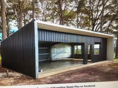 a black metal building sitting in the middle of a forest