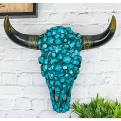 a bull's head made out of glass beads on a white brick wall next to a potted plant