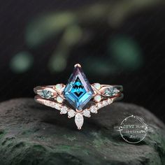 a ring with an aqua blue topazte and white diamonds on it sitting on a rock