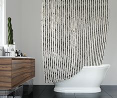 a white bath tub sitting next to a wooden sink and toilet in a bathroom under a window