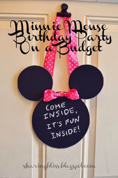 a minnie mouse birthday party on a budget sign with pink polka dots and a bow hanging from the front door