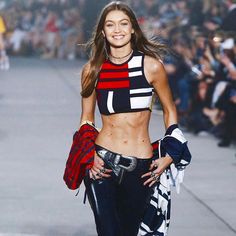 a model walks down the runway in a crop top and leather pants with her hands on her hips