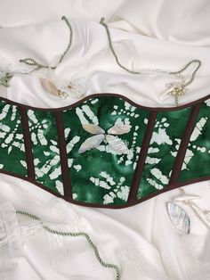 Inspired by the Green Darner Dragonfly, with forest green-patterned cotton and mother-of-pearl "wings" adorning the center *Size Small (4-6) This is a lined and interfaced corset with plastic boning that is sturdy, but it is a fashion corset. will include a white ribbon for lacing unless another color is requested. Green Strapless Corset With Boned Bodice, Green Dress From Burlesque, Green And Black Corset, Green Underbust Corset, Luxury Green Bustier Corset, Floral Print Underbust Corset, Fashion Corset, Underbust Corset, White Ribbon