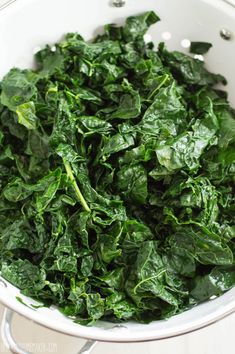 a white bowl filled with greens on top of a table