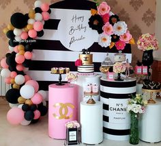 a table topped with lots of cakes and desserts covered in pink, black, white and gold balloons