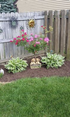 a small garden with flowers and a welcome sign in the middle of it's flower bed