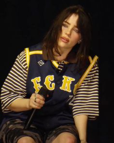 a woman sitting on the ground with a microphone in her hand and wearing a striped shirt