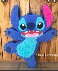 a blue and pink stuffed animal hanging on a wooden wall