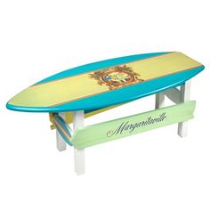 a toy surfboard sitting on top of a table next to a sign that says margarita beach