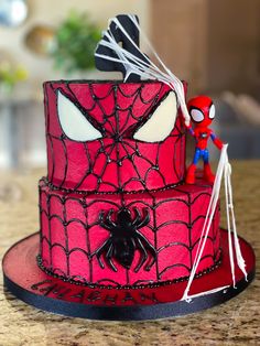 a spiderman cake is on a table with a spider - man figurine