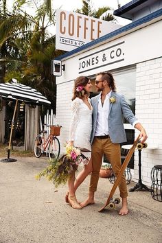 a man and woman standing next to each other in front of a coffee shop with their skateboards