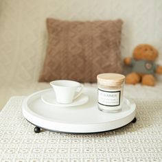 a cup and saucer on a tray with a teddy bear in the back ground