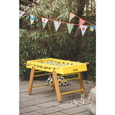 a yellow foosball table sitting on top of a brick patio