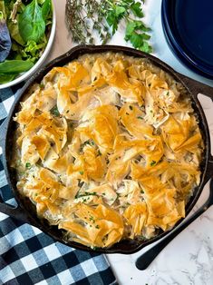 a casserole dish with chicken and spinach in it on a checkered table cloth