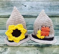 two crocheted hats with sunflowers and leaves on them sitting next to each other