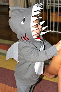 a little boy in a shark costume playing with a cell phone