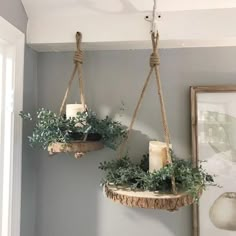 two hanging planters with candles and greenery on them in the corner of a room