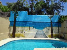 an empty swimming pool with palm trees painted on the wall and steps leading up to it