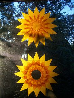 two paper sunflowers sitting on top of a window