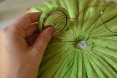 a person holding a green parasol in their left hand and threading it together