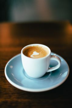 a cup of coffee sitting on top of a blue saucer next to a wooden table