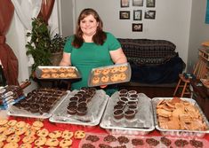 a woman holding trays of cookies and pastries