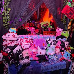 a pile of stuffed animals sitting on top of a blue bench in front of a black curtain