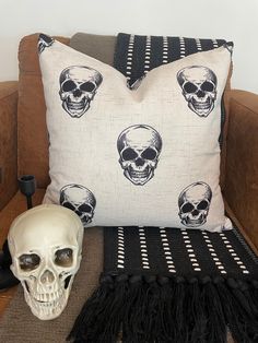 a white skull sitting on top of a couch next to a black and white pillow