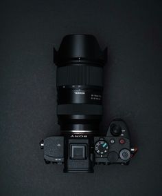 a camera with a lens attached to it's body, sitting on a black surface