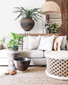 a living room filled with lots of furniture and plants on top of the couches