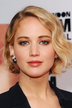 a close up of a person with blonde hair and blue eyeshadow wearing earrings