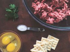 ingredients to make meatball crackers in a bowl on a wooden table with spoons