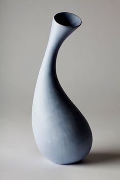 a large gray vase sitting on top of a white table next to a black object