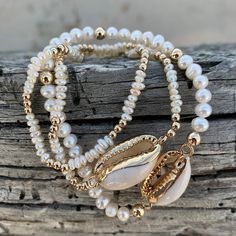 "Handmade stretch bracelet featuring pearls and a cowrie shell charm. So cute for resort / summer and stacks well with other bracelets! There are two sizes available: mini and standard. \"Mini\" consists of 3MM 14K gold beads and 3MM mini oval freshwater pearls. \"Standard\" consists of 4MM 14K gold beads and 4MM freshwater pearls.  Each bracelet is handmade to order and available in different sizes, though please note designs may vary slightly from listing photos depending on size. To find your Cowrie Shell Bracelet, Cowrie Shell Jewelry, Wax Cord Bracelet, Seashell Bracelet, Pearl Bracelet Wedding, Summer Beach Jewelry, Beachy Jewelry, White Pearl Bracelet, Ball Bracelet