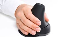 a person's hand holding a black mouse on a white surface with one thumb extended