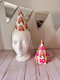 a white mannequin head wearing a party hat with photos on it next to a mirror