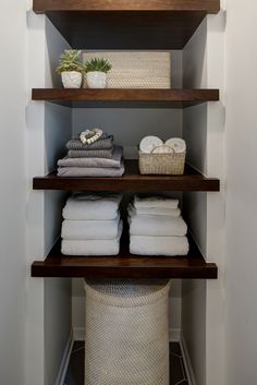 the shelves in this bathroom are filled with folded towels and other bath accessories, including baskets