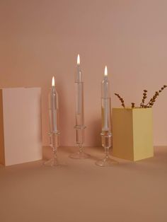 three candles are sitting on a table next to a vase with some flowers in it