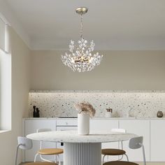 a dining room table with chairs and a chandelier hanging from it's ceiling