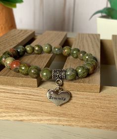 a bracelet with a heart charm and the word serenity on it sitting on top of a wooden box