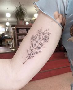 a woman's arm with a flower tattoo on the left side of her arm