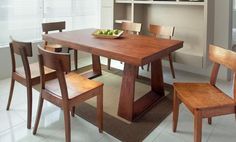 a dining room table with chairs and a bowl of fruit on the top of it