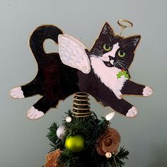 a black and white cat ornament on top of a christmas tree