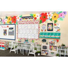 a classroom decorated with colorful flowers and calendars on the wall next to white chairs