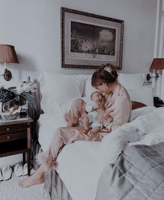 a woman sitting on top of a bed holding a baby